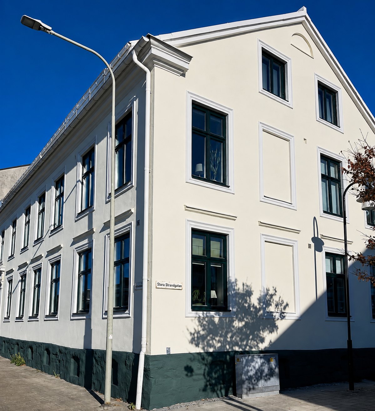 Renoverad fasad på vitt flerbostadshus med gröna fönster i Landskrona