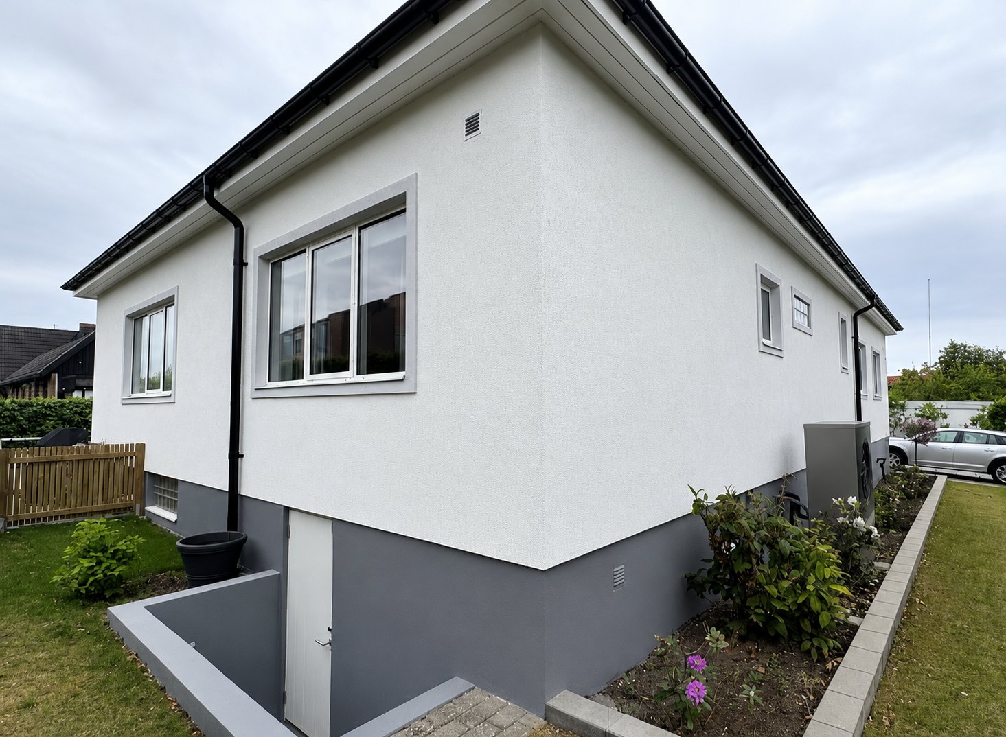 Nyputsad villa med vit fasad och grå sockel i Skåne
