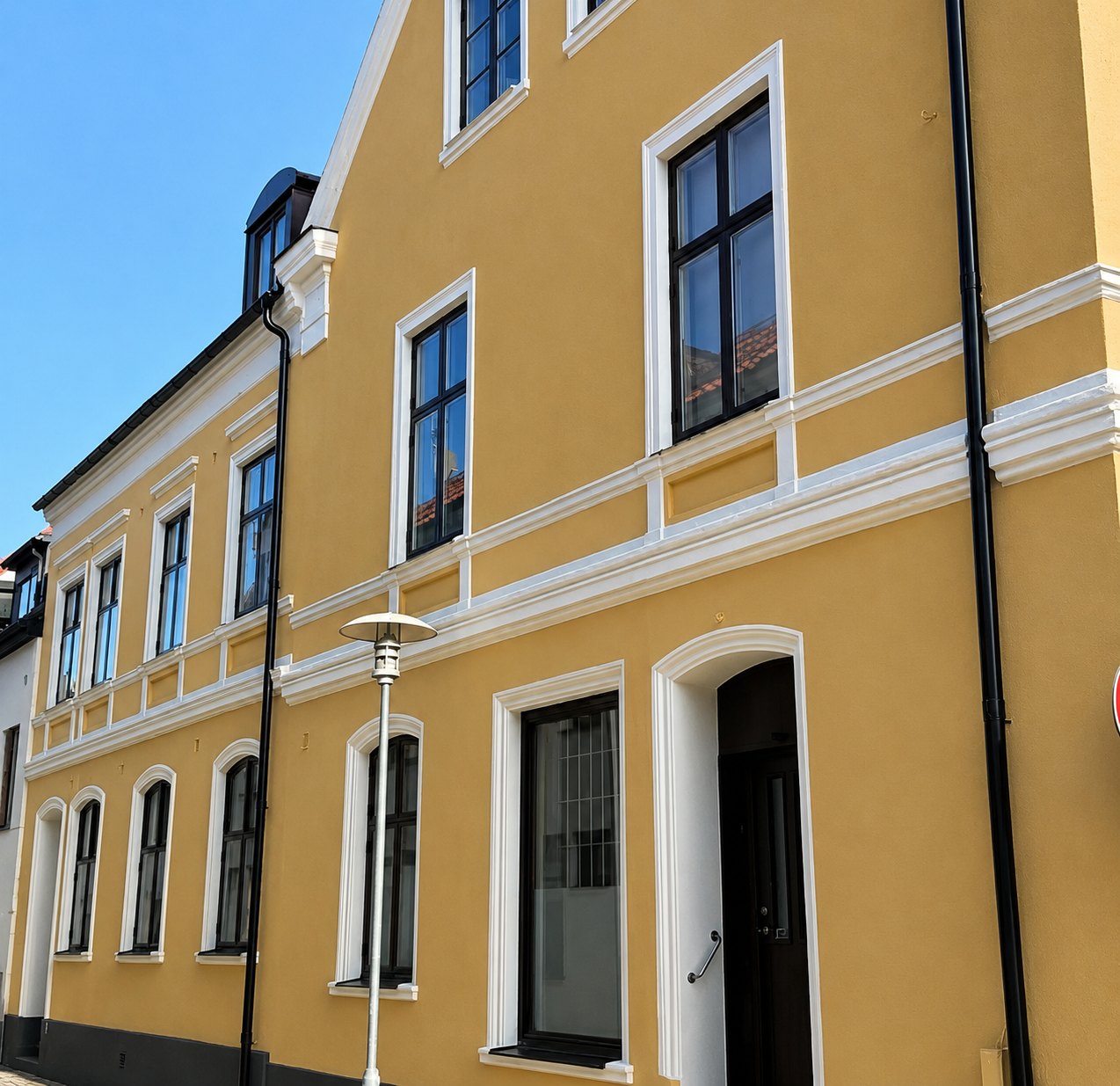Putsad fasad i gul kulör på klassisk byggnad i Landskrona